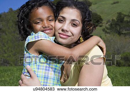 Stock Image - USA California, Fairfax, portrait of mother and daughter (6-7) hugging outdoors. Fotosearch
