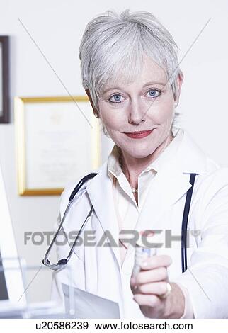 Stock Photo - USA, California, Fairfax, Portrait of female doctor holding pill bottle. Fotosearch