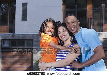 Stock Photo - USA California, Fairfax, portrait of parents with daughter (6-7) in front of house. Fotosearch