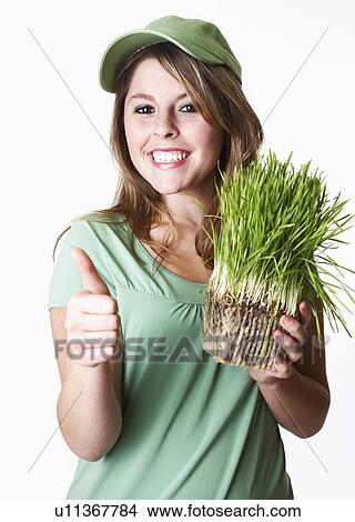 USA California, Fairfax, studio portrait of smiling young woman holding wheat grass View Large Photo Image Picture - USA California, Fairfax, studio portrait of smiling young woman holding wheat grass. Fotosearch
