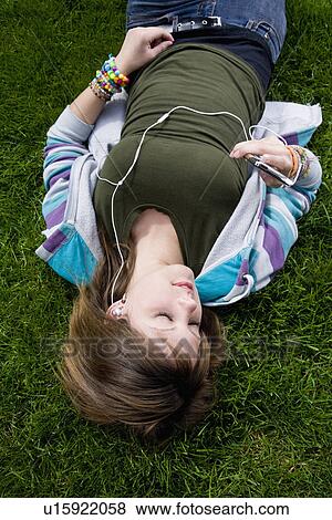 Stock Photo - USA California, Fairfax, teenage girl (16-17) lying on grass and listening music. Fotosearch