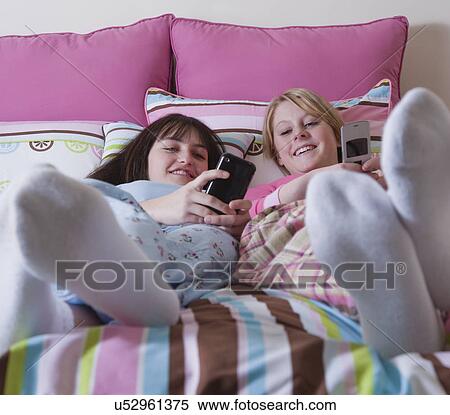 USA California, Fairfax, two teenage girls (14-15, 16-17) lying on bed and looking at mobile phones View Large Photo Image Stock Photography - USA California, Fairfax, two teenage girls (14-15, 16-17) lying on bed and looking at mobile phones. Fotosearch