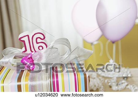 Stock Image - USA, California, La Quinta, Birthday gift with number sixteen, balloons in background. Fotosearch