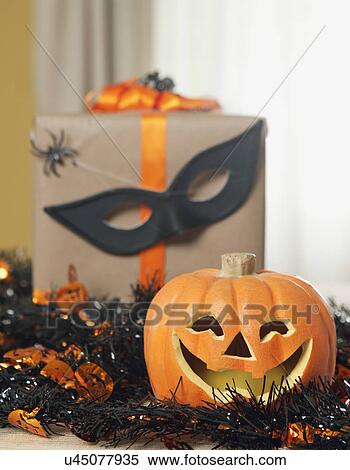 Stock Photography - USA, California, La Quinta, Jack o' lantern and garland, Halloween gift with spiders and mask in background. Fotosearch