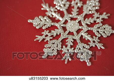 Stock Image - USA, California, La Quinta, Silver snowflake against red background. Fotosearch