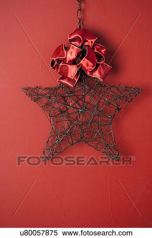 Stock Photography - USA, California, La Quinta, Wire star and bow against red background. Fotosearch