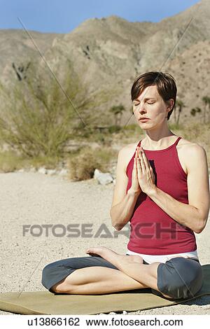 Stock Image - USA, California, La Quinta, Woman meditating in desert landscape. Fotosearch