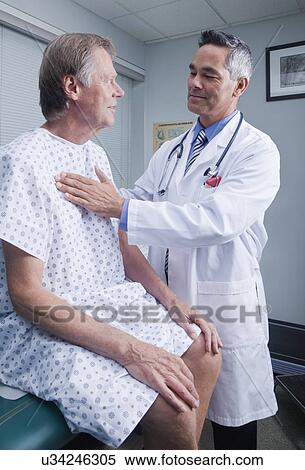 Stock Photography - USA California, Larkspur, Doctor talking to patient in hospital gown. Fotosearch
