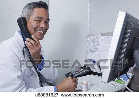 USA California, Larkspur, Portrait of male doctor talking on phone and writing prescription at desk View Large Photo Image Stock Photo - USA California, Larkspur, Portrait of male doctor talking on phone and writing prescription at desk. Fotosearch