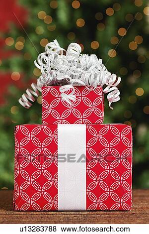 Stock Photo - USA, California, Lawndale, Christmas gift in stack, Christmas tree in background. Fotosearch