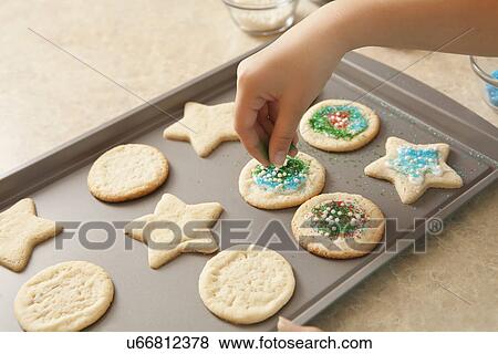 Stock Photo - USA, California, Lawndale, Close-up of girl (10-11) topping cookies with sprinkles. Fotosearch