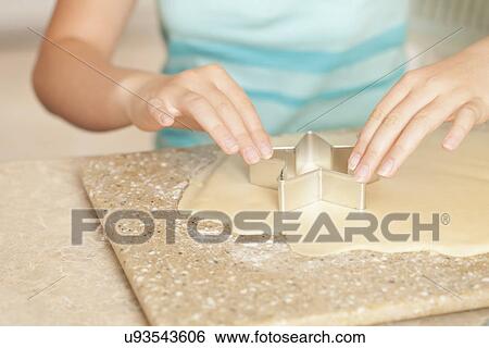 Stock Photograph - USA, California, Lawndale, Close-up of girl (10-11) using pastry cutter on dough. Fotosearch