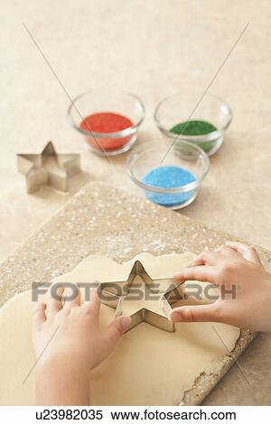 Stock Photography - USA, California, Lawndale, Close-up of girl (10-11) using pastry cutter on dough. Fotosearch