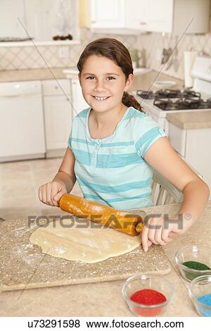 Stock Photo - USA, California, Lawndale, Girl (10-11) rolling dough. Fotosearch
