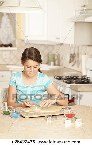 Stock Photography - USA, California, Lawndale, Girl (10-11) using pastry cutter on dough. Fotosearch