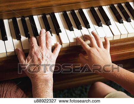 Stock Photo - USA, California, Lawndale, Grandmother and granddaughter (8-9) playing piano, close-up on hands. Fotosearch