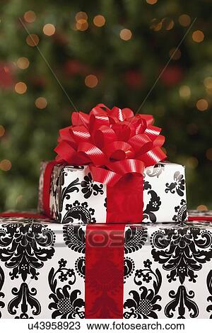 Stock Image - USA, California, Lawndale, Stack of presents, christmas tree in background. Fotosearch