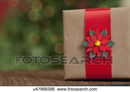 Stock Photo - USA, California, Lawndale, Wrapped Christmas gift with poinsettia decoration. Fotosearch