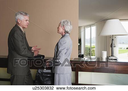 Stock Image - USA, California, Mill Valley, Business man and woman talking at hotel reception. Fotosearch