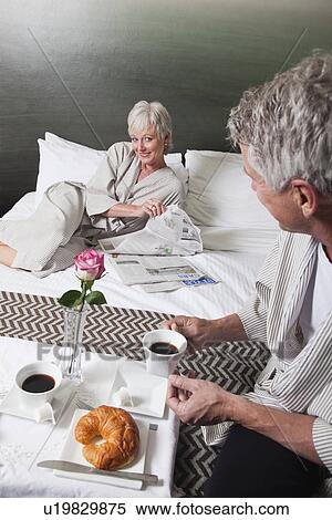 Stock Photography - USA, California, Mill Valley, Couple relaxing on bed with breakfast. Fotosearch