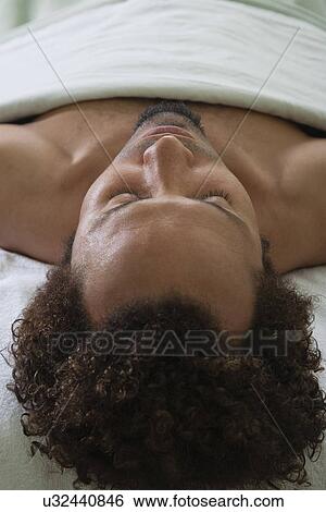Stock Photograph - USA, California, Oakland, man lying on massage bed. Fotosearch