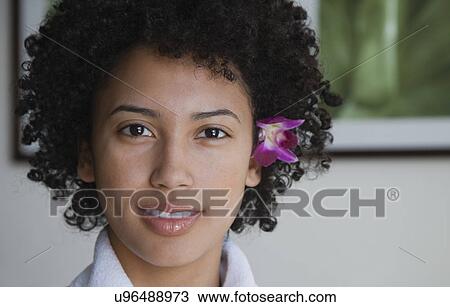 Stock Image - USA, California, Oakland, portrait of young woman with orchid in hair. Fotosearch