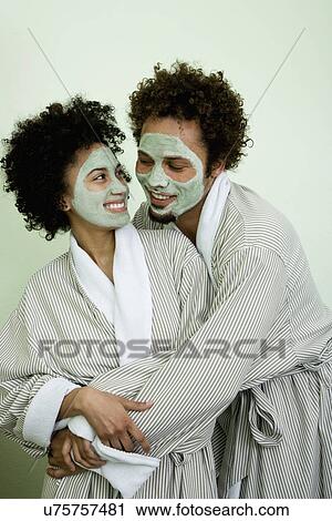 Stock Image - USA, California, Oakland, smiling couple with facial masks embracing. Fotosearch