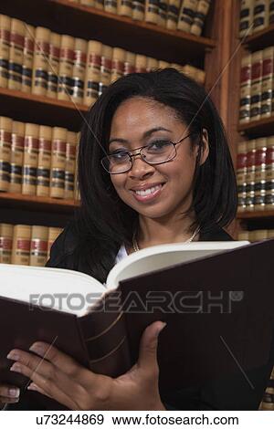 Stock Photo - USA, California, Oakland, Woman reading books in library. Fotosearch
