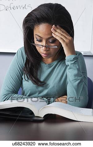 Stock Image - USA, California, Oakland, Young woman reading textbox. Fotosearch