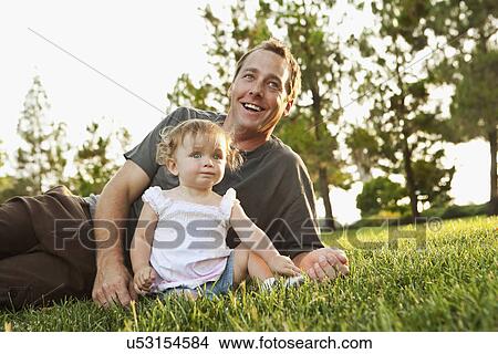 USA, California, Rancho Cucamonga, Father with daughter (12-17 months) relaxing on grass View Large Photo Image Picture - USA, California, Rancho Cucamonga, Father with daughter (12-17 months) relaxing on grass. Fotosearch