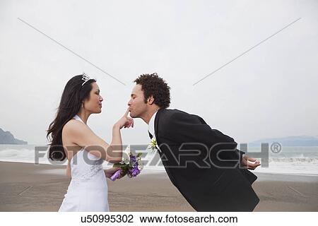 Stock Image - USA, California, San Francisco, Baker Beach, bride and groom on beach. Fotosearch