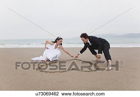 USA, California, San Francisco, Baker Beach, bride and groom drawing heart in sand on beach View Large Photo Image Stock Image - USA, California, San Francisco, Baker Beach, bride and groom drawing heart in sand on beach. Fotosearch