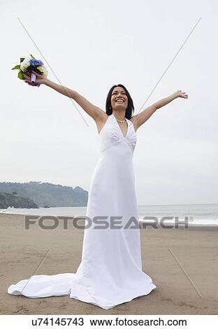 Stock Image - USA, California, San Francisco, Baker Beach, bride with bouquet on beach. Fotosearch