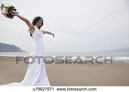 Stock Image - USA, California, San Francisco, Baker Beach, bride with bouquet on beach. Fotosearch