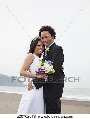 Stock Photo - USA, California, San Francisco, Baker Beach, bride and groom embracing on beach. Fotosearch