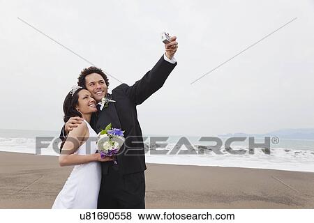 USA, California, San Francisco, Baker Beach, bride and groom on beach taking self photo View Large Photo Image Stock Photo - USA, California, San Francisco, Baker Beach, bride and groom on beach taking self photo. Fotosearch