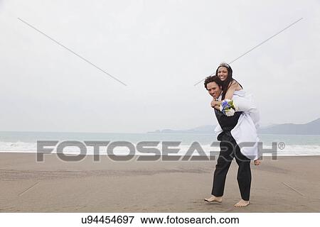 Stock Photo - USA, California, San Francisco, Baker Beach, bride and groom on beach. Fotosearch