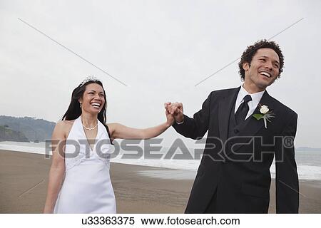 Stock Photography - USA, California, San Francisco, Baker Beach, bride and groom on beach. Fotosearch