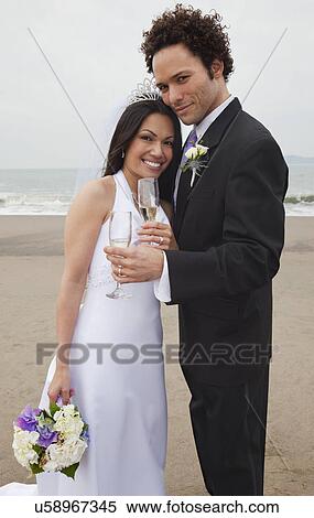 Stock Photography - USA, California, San Francisco, Baker Beach, bride and groom toasting on beach. Fotosearch