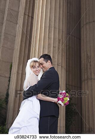 Stock Image - USA, California, San Francisco, bride and groom embracing outdoors. Fotosearch