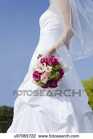 Stock Image - USA, California, San Francisco, bride holding bouquet outdoors. Fotosearch