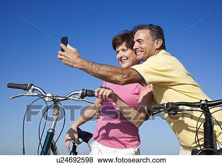 Stock Photo - USA, California, San Francisco, Couple with bicycles standing against blue sky. Fotosearch