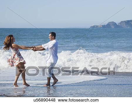 Stock Photo - USA, California, San Francisco, couple holding hands on Baker Beach. Fotosearch