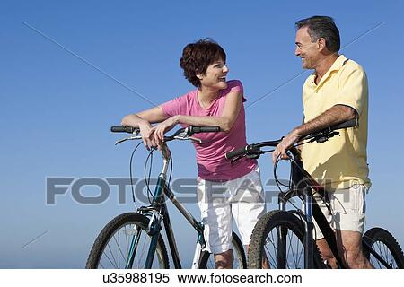 Stock Photography - USA, California, San Francisco, Couple with bicycles standing against blue sky. Fotosearch
