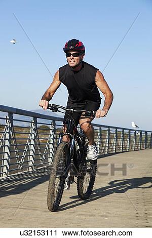 Stock Image - USA, California, San Francisco, Cyclist on wood boardwalk. Fotosearch