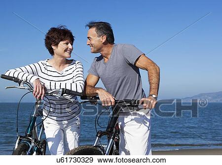 Stock Photo - USA, California, San Francisco, Elder couple cycling on beach. Fotosearch