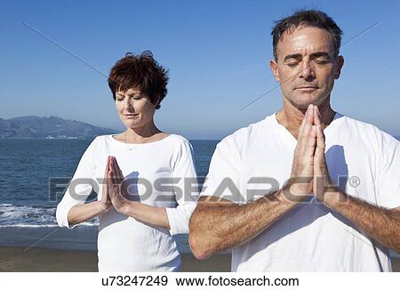 Stock Photo - USA, California, San Francisco, Elder couple practicing yoga on beach. Fotosearch