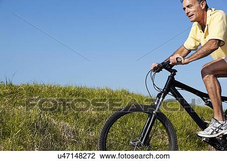 Stock Image - USA, California, San Francisco, Man cycling among meadow. Fotosearch