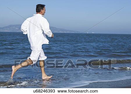 Stock Image - USA, California, San Francisco, Man jogging on beach. Fotosearch