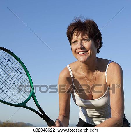 Stock Image - USA, California, San Francisco, Mature woman playing tennis. Fotosearch